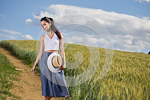 Girl is walking along the road among the fields