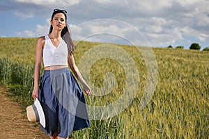 Girl is walking along the road among the fields