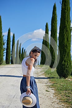 Girl is walking along the road among the fields