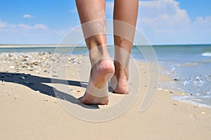 Girl walking barefoot on the sand of the sea beach