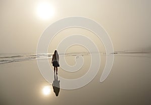 Girl walking on beautiful foggy beach.
