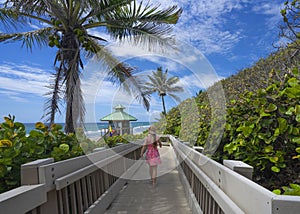 Girl walking on boardwalk to beautiful Florida beach.