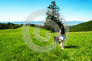 Girl walking with dog on green meadow