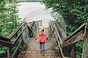 Girl walking down wooden stairs to water at Canadian Ontario Kettles lake in Midland. Canada forest nature.