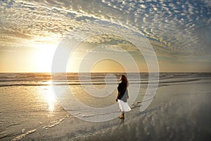 Girl walking and enjoying on beautiful beach at sunrise.