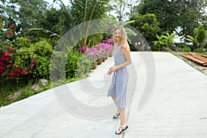 Girl walking in exotic park near plams and flowers.