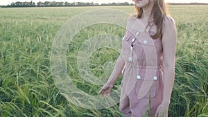 Girl walking in field stroking spikelets of wheat with hand, young woman enjoying summer nature at sunset, concept of harmony man