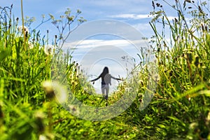 Girl is walking on flowering meadow enjoying peaceful nature