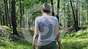 Girl walking in the green forest. Back view, slow motion, 4K