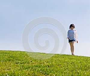 Girl walking on the green hill