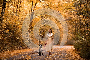 Girl is walking with her dog. Warm autumn. Portrait of a beautiful woman in a light dress. Beautiful young brunette