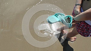 Girl is walking, her footprints are washed by waves.