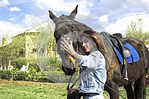 Girl is walking in nature and posing near a horse