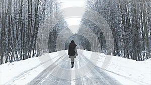 Girl walking on the road to the winter woods