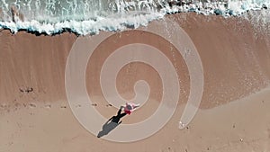 Girl walking on seashore.  Close up aerial top view of girl walking on beach. Woman in red outfit on coastline. Footprint in sand.