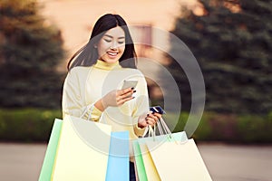 Girl walking with shopping bags and texting on phone