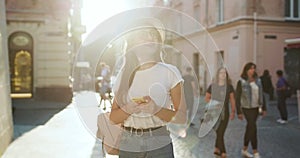 Girl walking in the street and Texting SMS on her Mobile Phone. Attractive young Woman in a stylish look Using APP on