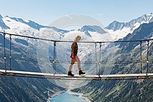 Girl Walking on a Suspension Bridge Watching an Alpine Mountain Landscape