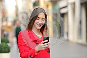 Girl walking and texting on the smart phone in the street in red