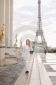 Girl walking on Trocadero square near gilded statues and Eiffel Tower.