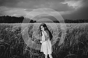 Girl walking on a wheat field holding wheat spike at beautiful sunset. Freedom and fresh air concept.