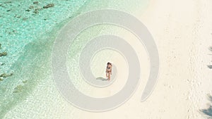Girl walking on white beach on tropical island resort in Maldives