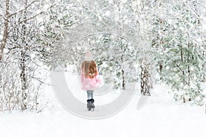 Girl walking in the winter forest, backview