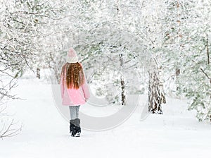 Girl walking in the winter forest, backview photo