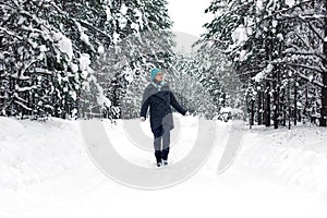 A girl is walking in the winter snowy forest.