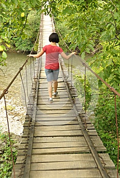 Girl walking on a wooden bridge over a river