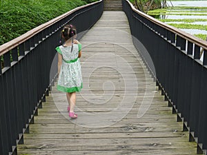 Girl walking on the wooden footbridge photo