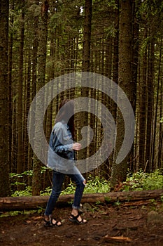 A girl walking on the woods, traveler in romanian carpathian mountains, wears in denim clothes. Vertical view