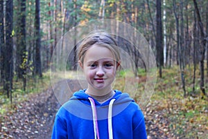 A girl walks alone while walking through the forest on an autumn day. Loneliness and melancholy. A young girl in a blue