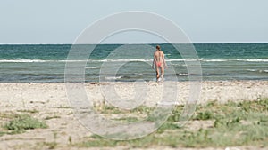 A girl walks along the coast towards the sea alone