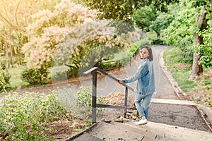 Girl walks along the path in the city park and looking at the blooming trees at spring time