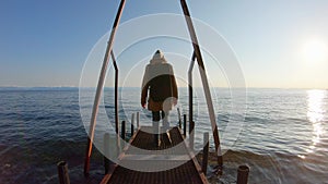 Girl walks along the pier to the water of lake Baikal