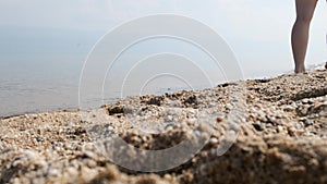 Girl walks along the sandy beach. Close up of woman`s legs
