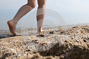 Girl walks along the sandy beach. Close up of woman`s legs