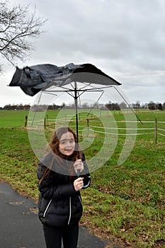 Girl walks with broken umbrella through the storm