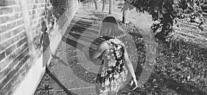 The girl walks energetically along the road, waving her arms. Back view. Black and white monochrome image. Stylized in