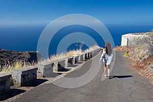 Girl walks in the middle of the coastal road