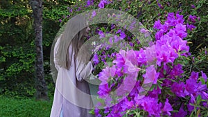 Girl walks over a large flower bed of bright flowers and looks at the camera