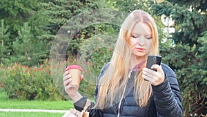 girl walks in the park with big purchases after shopping, talking on the phone. Happy girl using a smart phone in a city