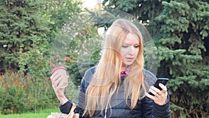 girl walks in the park with big purchases after shopping, talking on the phone. Happy girl using a smart phone in a city