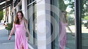 A girl walks past a glass building Canada Vancouver Wind blows smiling young woman In city center, young girl in pink