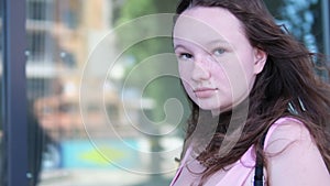 A girl walks past a glass building Canada Vancouver Wind blows smiling young woman In city center, young girl in pink