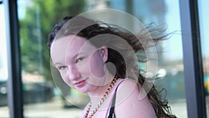 A girl walks past a glass building Canada Vancouver Wind blows smiling young woman In city center, young girl in pink