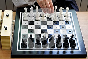 The girl walks a pawn in the debut of the chess game. Special kit for the blind or travelers