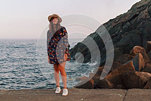 The girl walks on the pier in sunny weather and admires the sea scenery