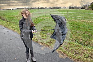 Girl walks through rain and storm, her umbrella is broken